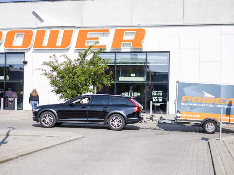 Bil med gratis Freetrailer foran POWER-butik – viser stærk synlighed og kundeservicefordel ved at blive partner.